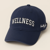 Healthy Gal™ Wellness Classic Cap in navy with white varsity "WELLNESS" embroidery on the front and "Healthy Gal" script on the side, beige background