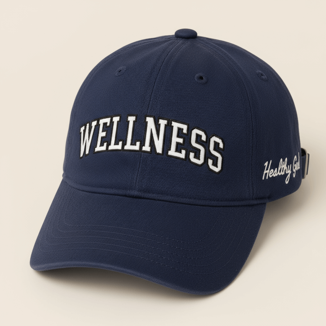 Healthy Gal™ Wellness Classic Cap in navy with white varsity "WELLNESS" embroidery on the front and "Healthy Gal" script on the side, beige background
