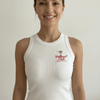 Woman smiling in the Healthy Gal™ Wellness Club Tank in white, showing the embroidered palm tree and cursive logo against a plain background